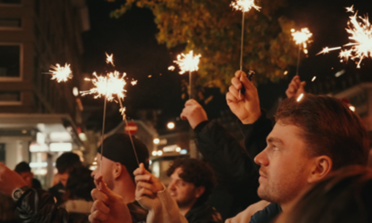 Eine Gruppe von Menschen hält Sparklers in der Dunkelheit, während sie in einer städtischen Umgebung feiern.