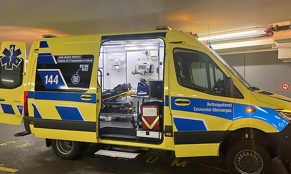 Ein Rettungswagen mit geöffneter Hintertür, ausgestattet mit medizinischer Ausrüstung und einer Trage.